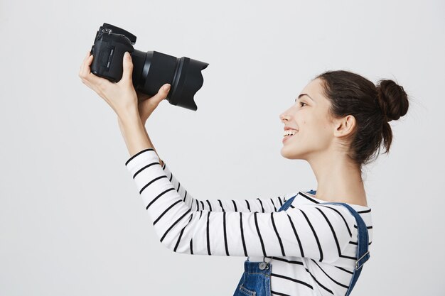 Бесплатное фото Милая и взволнованная девушка-фотограф, делающая селфи на профессиональную камеру