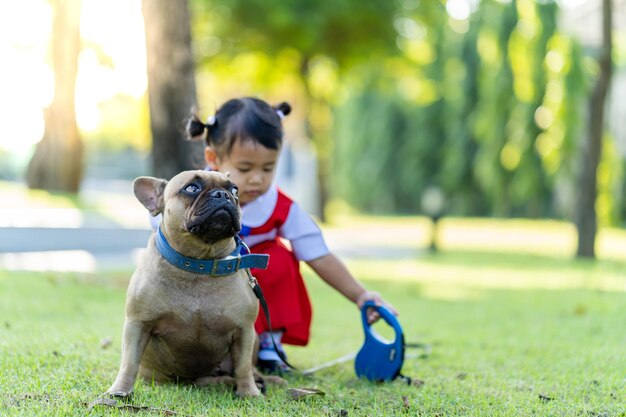 Cute Asian female child with her pet dog in a park