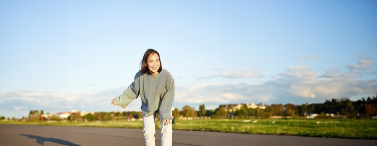 無料Photo 可愛いアジアの女の子がスケートボードを乗り ⁇ 道路でスケートを滑り ⁇ クルーザー・ロングボードで笑顔のスケートを楽しんでいます ⁇ 