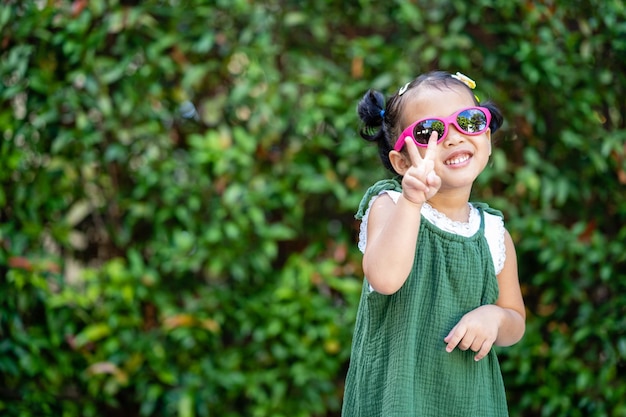 Cute Asian small girl in sunglasses happily posing