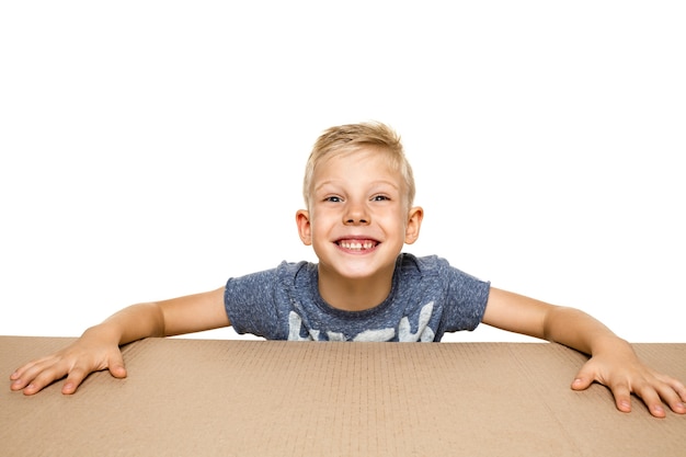 Cute, astonished little boy opening the biggest package. Shocked, happy young male model on top of cardboard box