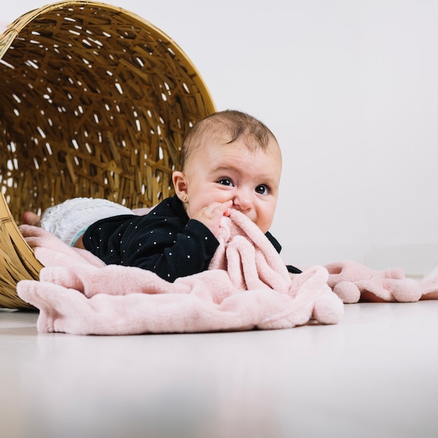 cute baby in basket chewing blanket