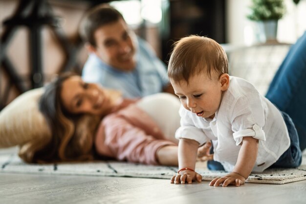 Cute baby boy spending time with his parents and crawling on the floor at home