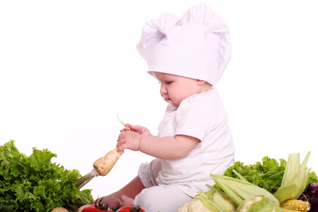 Free photo cute baby chef with different vegetables