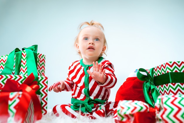 Cute baby girl 1 year old near santa hat posing over Christmas with decoration. Sitting on floor with Christmas ball