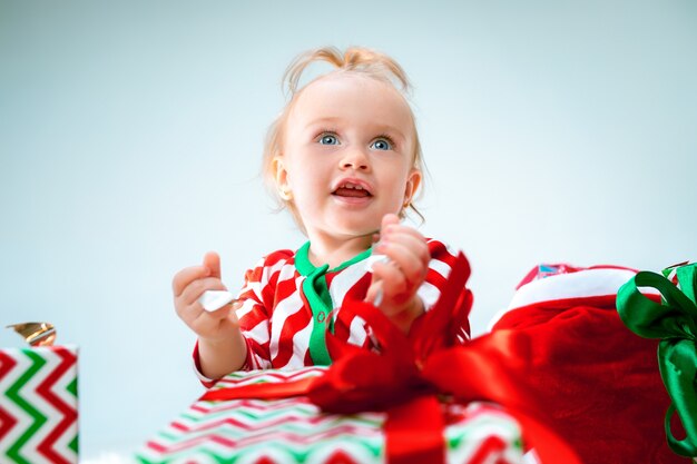 Cute baby girl 1 year old near santa hat posing over Christmas