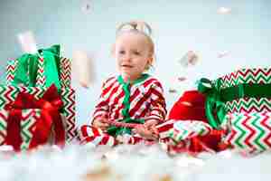Free photo cute baby girl 1 year old near santa hat posing over christmas
