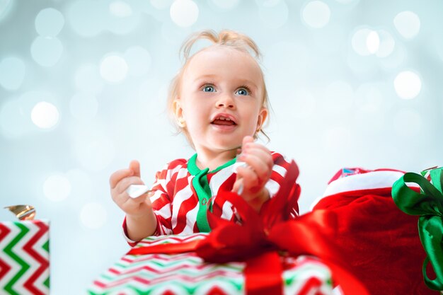 クリスマスボールと床に座っているサンタの帽子の近くのかわいい女の赤ちゃん1歳