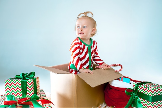 Милая девочка 1 год, сидя в коробке на фоне Рождества. Праздник, праздник, детская концепция