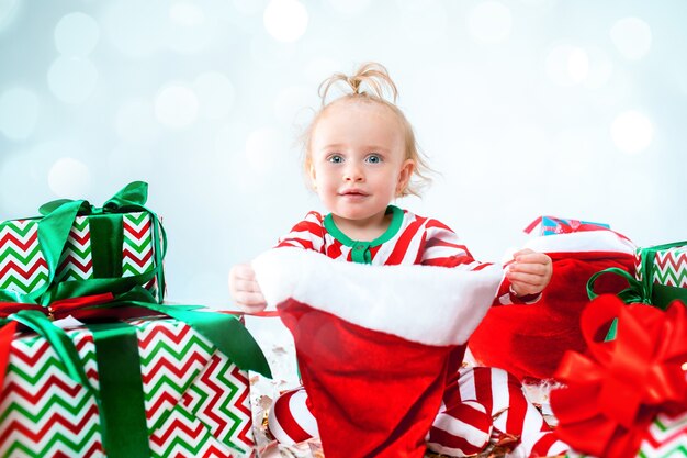 Cute baby girl 1 year old wearing santa hat posing over Christmas decorations