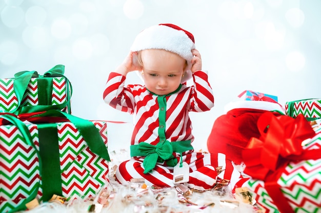 Cute baby girl 1 year old wearing santa hat posing over Christmas decorations