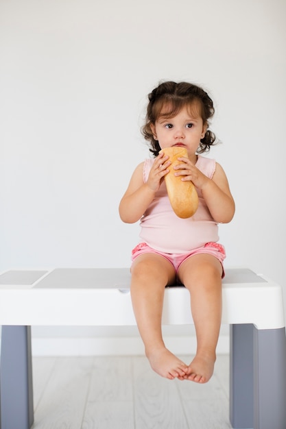 Free photo cute baby girl eating bread