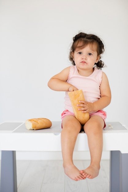 Cute baby girl playing with bread