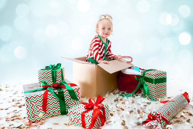 Милая девочка сидит в коробке на фоне Рождества. Праздник, праздник, детская концепция