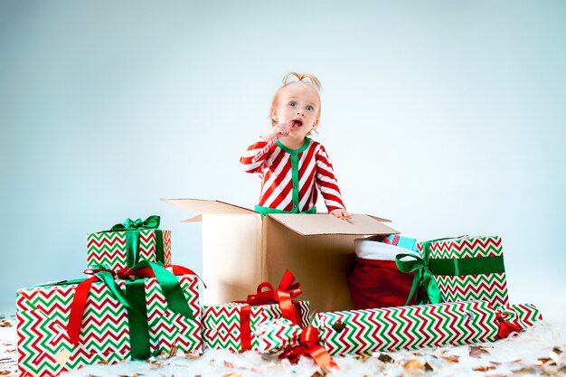 Cute baby girl sitting in box over Christmas background. Holiday, celebration, kid concept