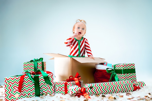 クリスマスの背景の上のボックスに座っているかわいい女の赤ちゃん。休日、お祝い、子供の概念