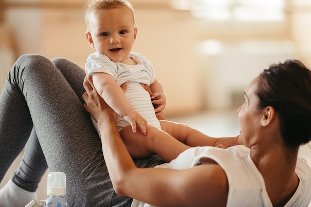 Cute baby having fun while being with his mother on exercise class in health club