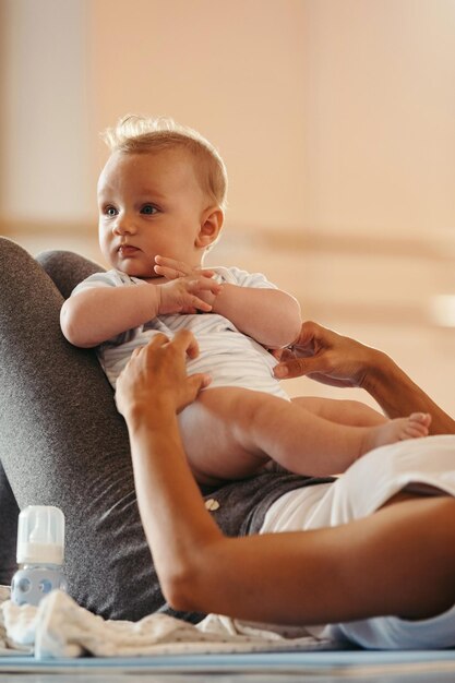 Cute baby and his unrecognizable mother during workout in a health club