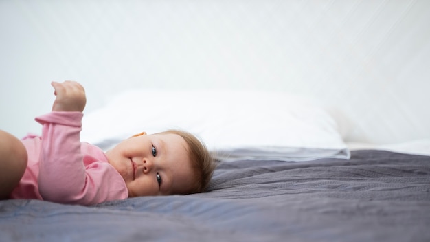 Cute baby laying in bed side view