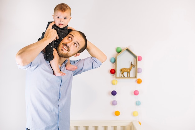 Cute baby riding on shoulders of father