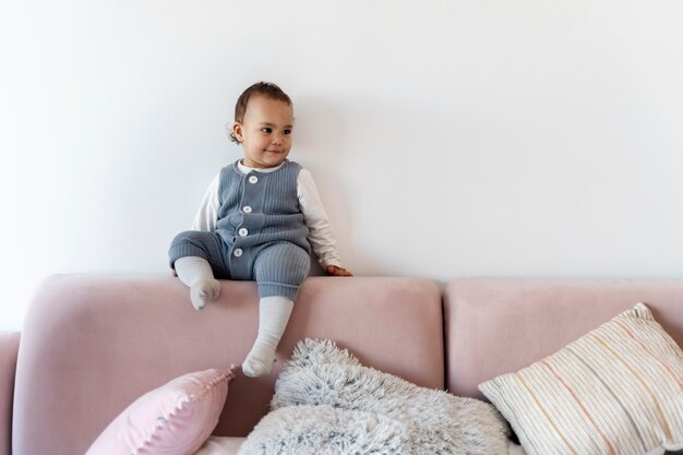 Cute baby sitting on top of the bed and smiling