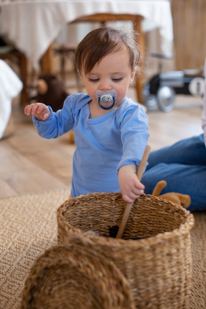 Free photo cute baby with pacifier playing medium shot