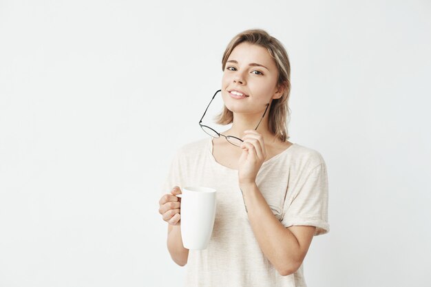 Cute beautiful girl smiling holding cup and glasses .