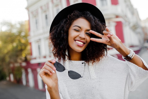 Cute black woman posing outdoor. Showing signs and smiling.