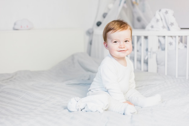 Cute blonde baby in white bed