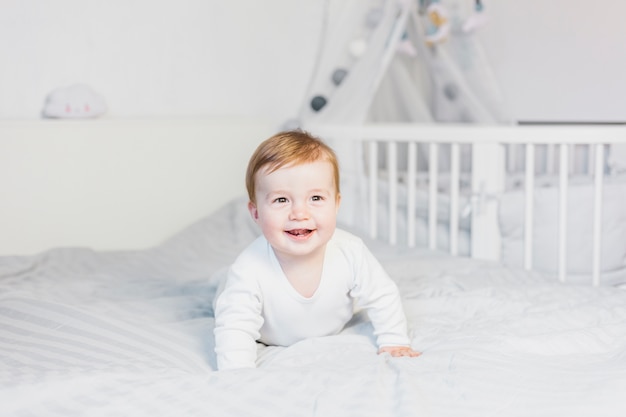 Cute blonde baby in white bed