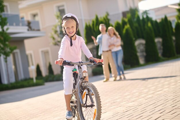 彼女の両親と一緒に自転車に乗ることを学ぶかわいいブロンドの女の子