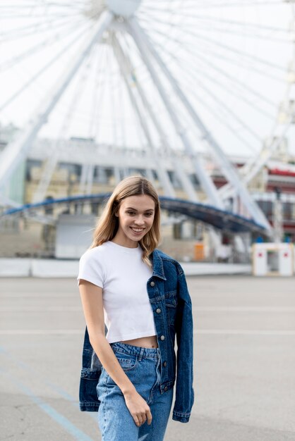 Cute blonde girl posing in front of ferris wheel