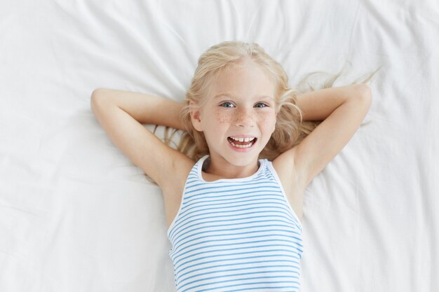 Cute blonde little girl in white bed