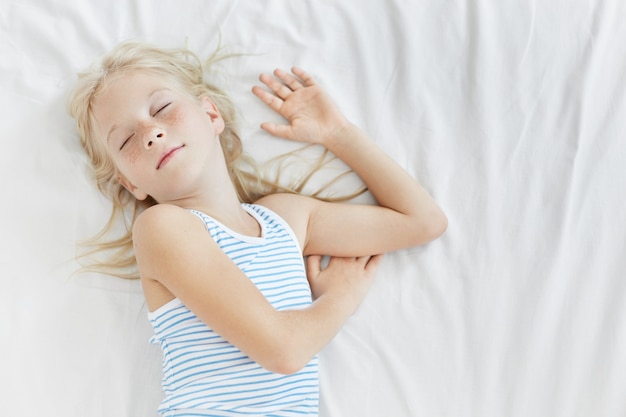 Free photo cute blonde little girl in white bed