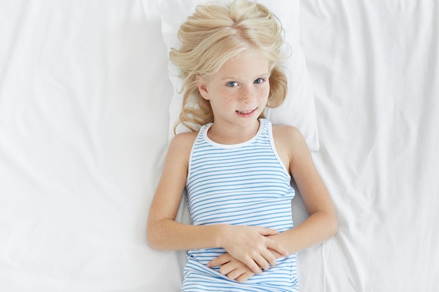 Cute blonde little girl in white bed