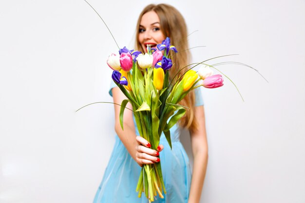 Cute blonde woman present to you spring bouquet of flowers, bright tulips, surprise , funny , holidays.