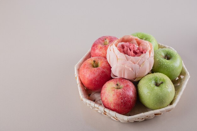 Милая коробка с яблоками на белой поверхности.