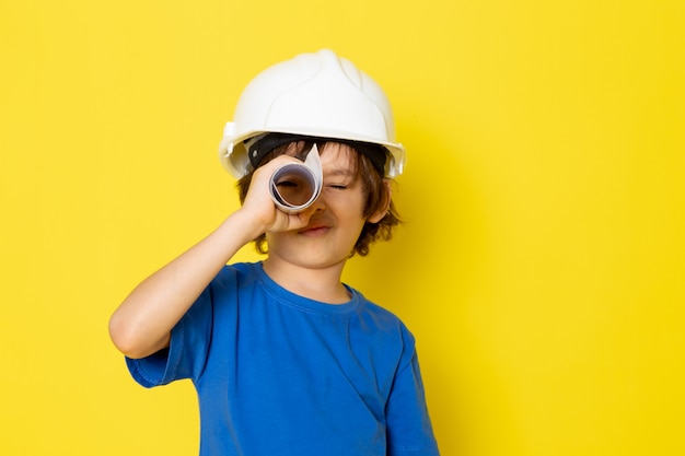 黄色の壁に紙を保持している青いtシャツでかわいい男の子かわいい