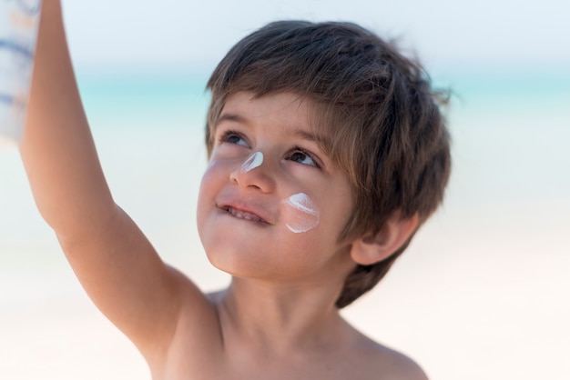 Foto gratuita ragazzo carino in spiaggia alzando lo sguardo