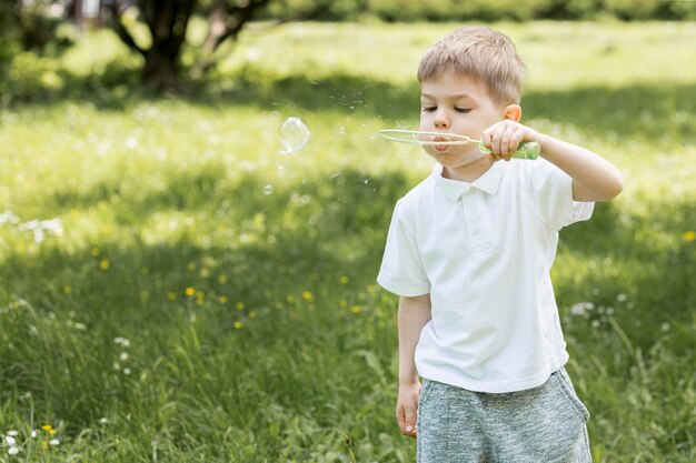 Cute boy blowing bubbles in the park