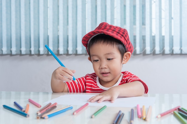 Cute boy draws with color pencils in the children's room