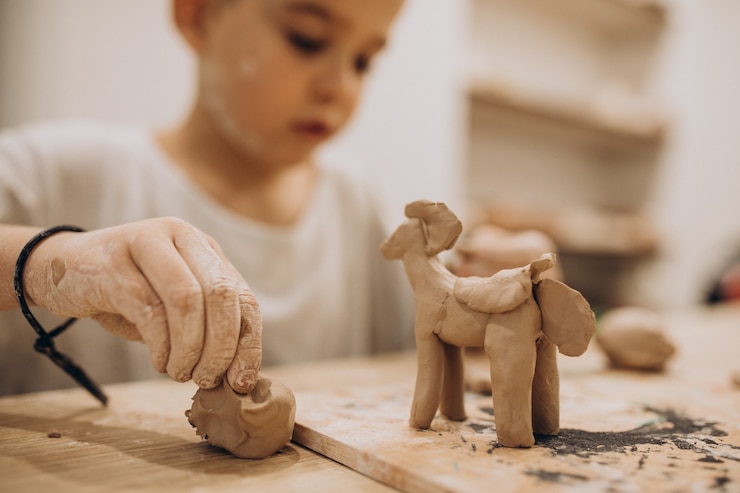 Free Photo cute boy forming toys from clay