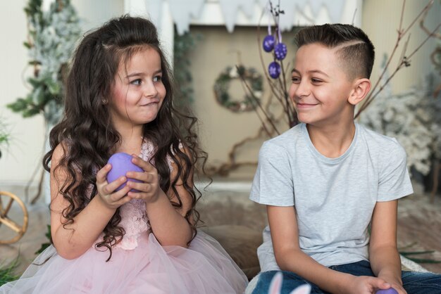 Cute boy and girl sitting with Easter eggs