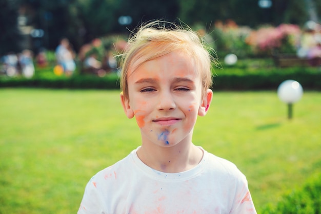 ホーリー祭の色で描かれたかわいい男の子。幸せな子供時代。カラフルな粉で遊んでいる10代前の少年。