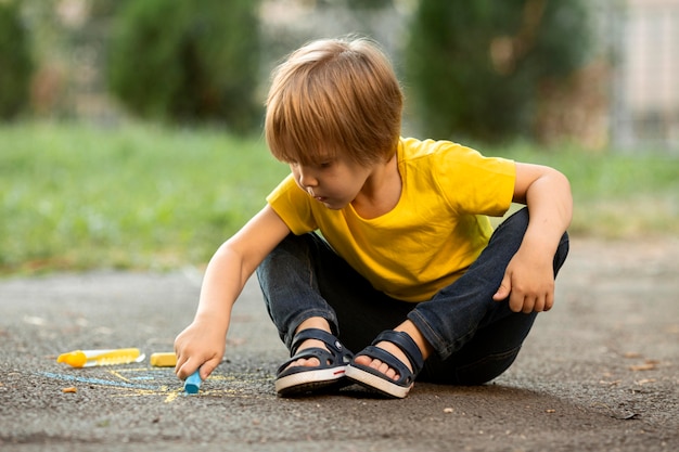 Cute boy in park drawing with chalk