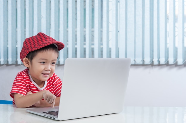 Free photo cute boy playing laptop in the children's room