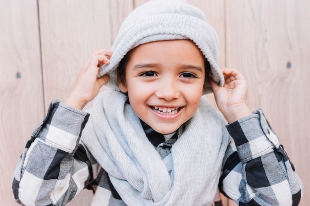 Free photo cute boy putting on winter cap