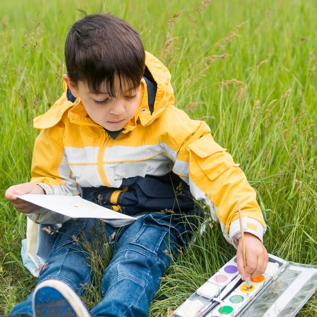 Cute boy in raincoat painting high view