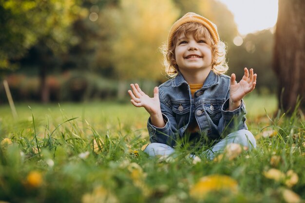 かわいい男の子は公園の芝生に座る