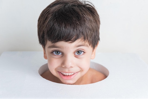 Ragazzo carino con la faccia nel buco del cerchio